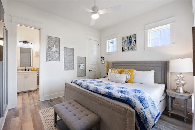 bedroom featuring ensuite bathroom, ceiling fan, light wood-type flooring, and sink