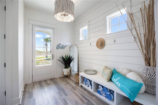 mudroom with hardwood / wood-style floors, wooden walls, a healthy amount of sunlight, and a notable chandelier