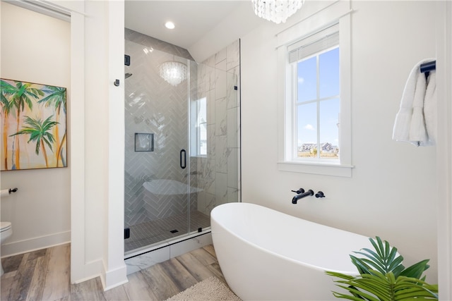 bathroom featuring plus walk in shower, wood-type flooring, and an inviting chandelier