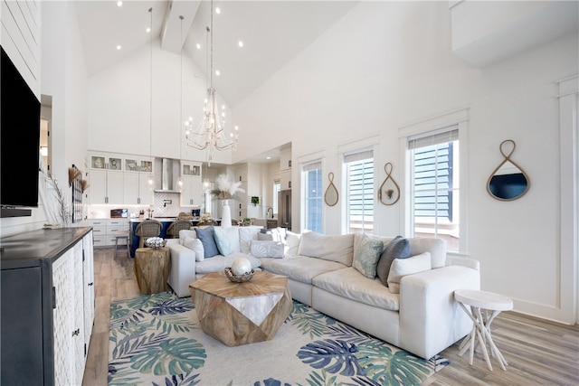 living room with beamed ceiling, wood-type flooring, a chandelier, and high vaulted ceiling