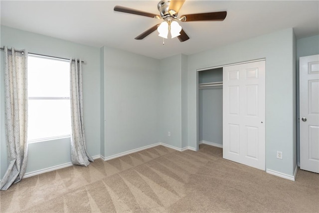 unfurnished bedroom featuring multiple windows, light colored carpet, and ceiling fan