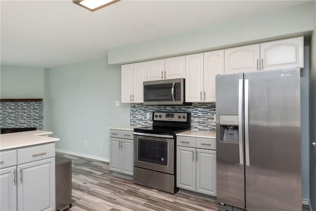 kitchen featuring backsplash, light wood-type flooring, white cabinetry, and stainless steel appliances