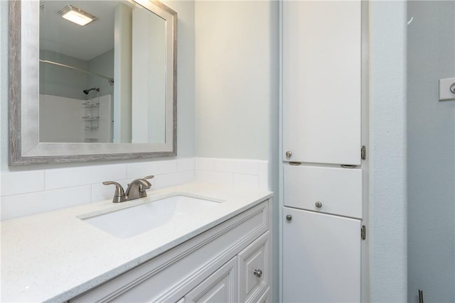 bathroom with decorative backsplash, a shower, and vanity