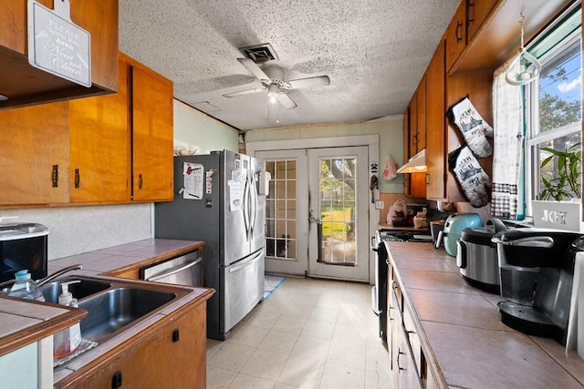 504 S 9th St, Aransas Pass, TX 78336 - kitchen with tile countertops, a ceiling fan, stainless steel appliances, under cabinet range hood, and a textured ceiling