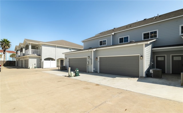 view of front of home with concrete driveway, central AC, and an attached garage