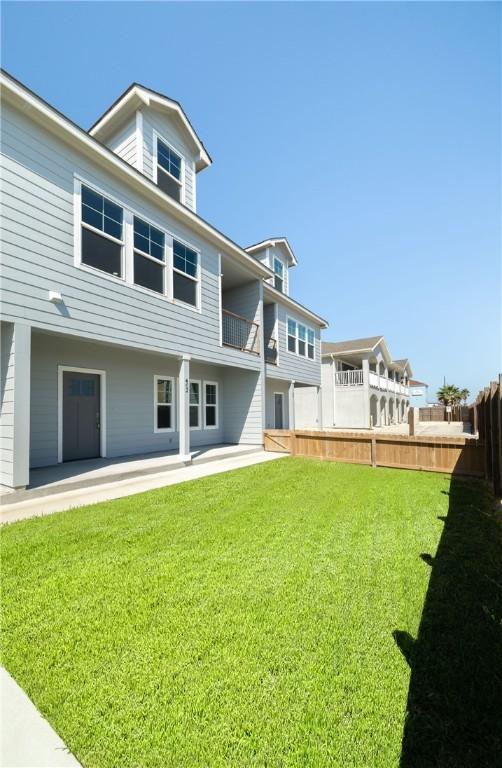 rear view of property with a yard, a patio, and fence