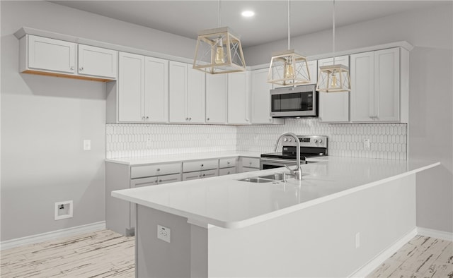 kitchen featuring light countertops, appliances with stainless steel finishes, a peninsula, and decorative light fixtures