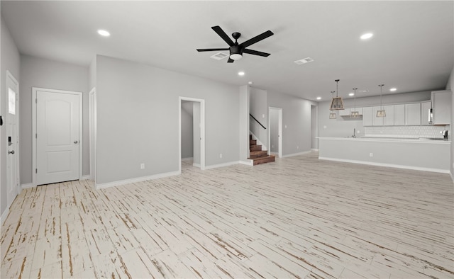 unfurnished living room featuring recessed lighting, visible vents, ceiling fan, and stairs