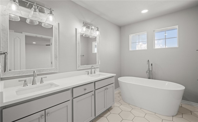 bathroom with a freestanding bath, a sink, and double vanity