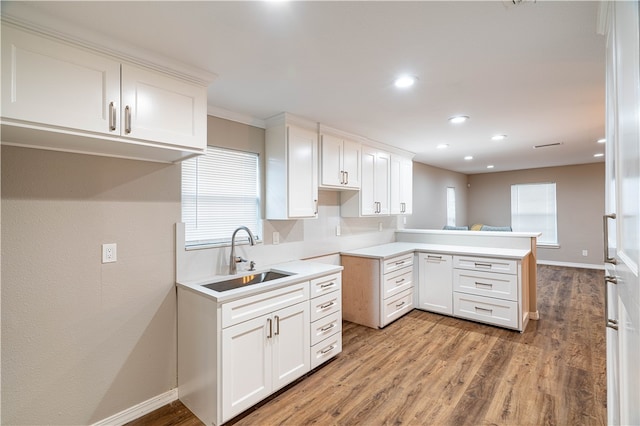 kitchen featuring white cabinets, kitchen peninsula, and sink