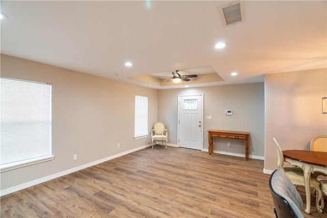 foyer entrance with hardwood / wood-style flooring, a raised ceiling, and ceiling fan