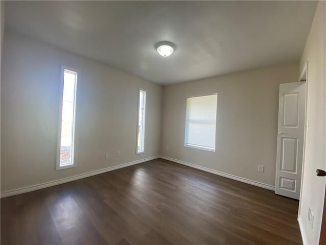 unfurnished room with baseboards, dark wood-style floors, and plenty of natural light
