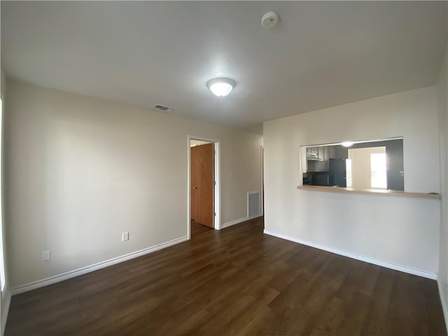 unfurnished living room featuring dark wood-style flooring, baseboards, and visible vents
