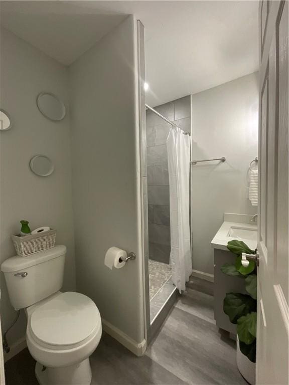 full bath with toilet, a stall shower, baseboards, and wood finished floors