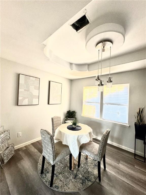 dining space featuring dark hardwood / wood-style flooring and a raised ceiling