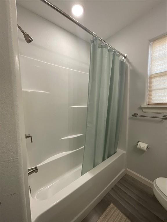 bathroom featuring toilet, shower / bath combo, baseboards, and wood finished floors