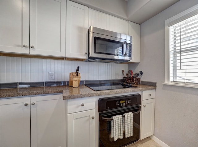 kitchen featuring black appliances, a healthy amount of sunlight, and white cabinets