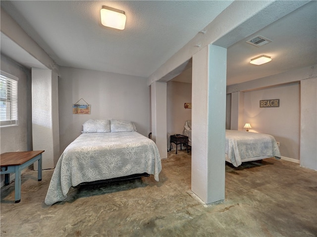 bedroom with concrete floors and a textured ceiling