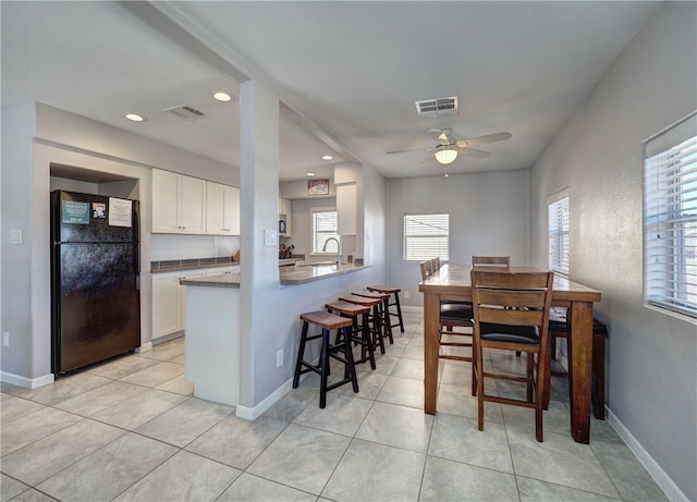 dining room featuring ceiling fan, sink, and light tile patterned flooring