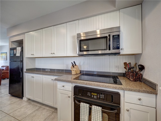 kitchen featuring light tile patterned flooring, white cabinetry, light stone countertops, and black appliances