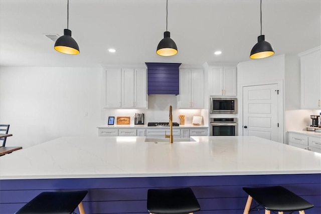 7910 Parham Dr, Corpus Christi, TX 78414 - kitchen with appliances with stainless steel finishes, white cabinets, a kitchen bar, and recessed lighting