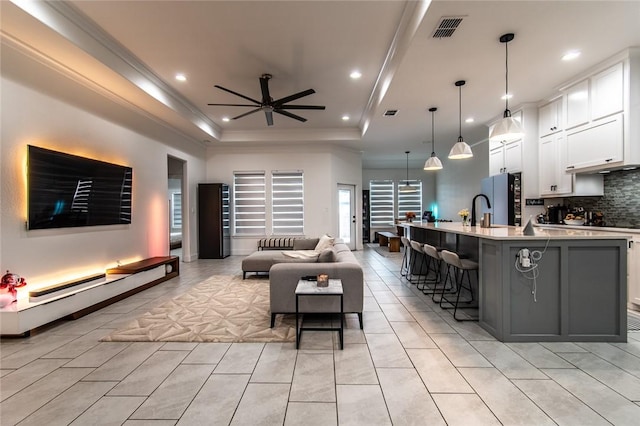 6730 Effat Dr, Corpus Christi, TX 78414 - living area with ceiling fan, a tray ceiling, recessed lighting, light tile patterned flooring, and crown molding