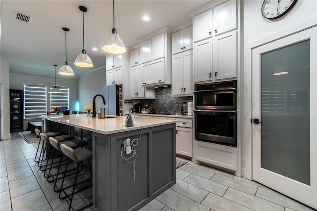 6730 Effat Dr, Corpus Christi, TX 78414 - kitchen with light tile patterned flooring, tasteful backsplash, a kitchen bar, an island with sink, and light countertops
