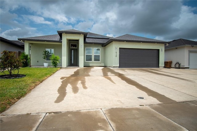 6730 Effat Dr, Corpus Christi, TX 78414 - prairie-style house featuring an attached garage, stucco siding, solar panels, a front yard, and concrete driveway