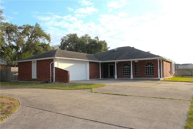 ranch-style home featuring a garage, concrete driveway, brick siding, and fence