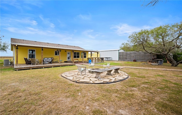 back of property with central AC unit, a fire pit, a yard, and a wooden deck