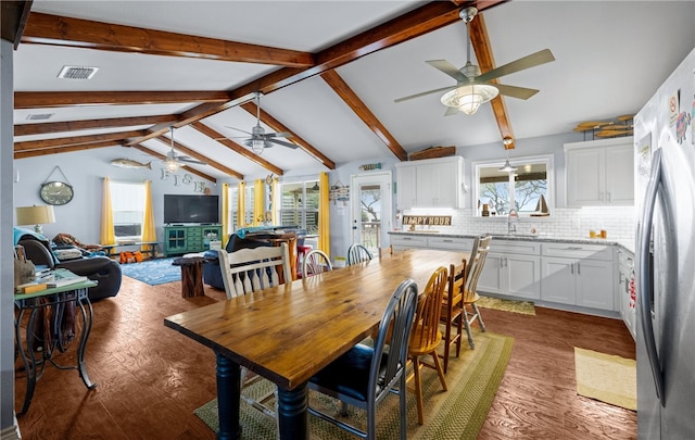 dining room featuring dark hardwood / wood-style flooring, vaulted ceiling with beams, and sink