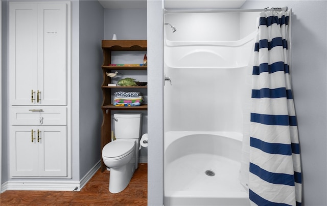 bathroom with a shower with curtain, hardwood / wood-style floors, and toilet