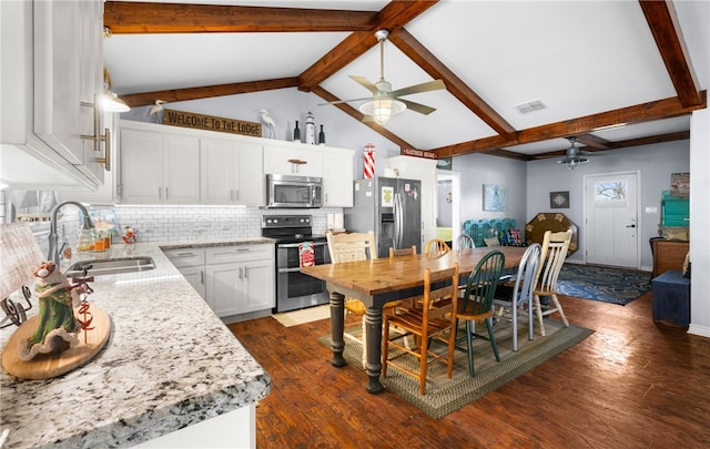 kitchen with dark wood-type flooring, sink, vaulted ceiling with beams, white cabinetry, and stainless steel appliances