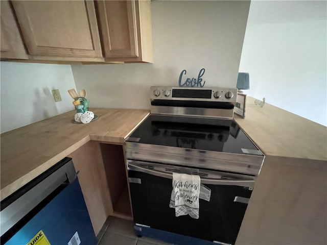 kitchen with wood counters, appliances with stainless steel finishes, light brown cabinets, and dark tile patterned floors