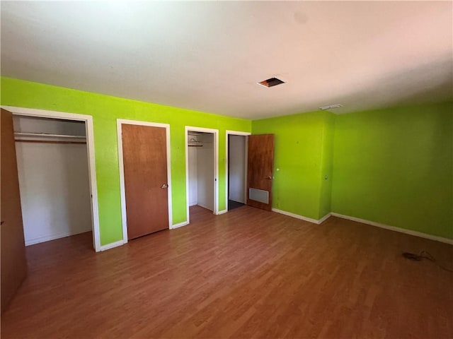 unfurnished bedroom featuring two closets and hardwood / wood-style flooring