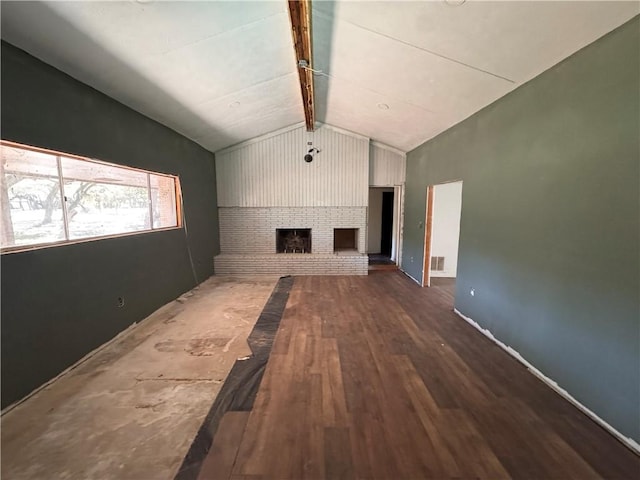 unfurnished living room featuring a fireplace, vaulted ceiling with beams, and dark hardwood / wood-style floors