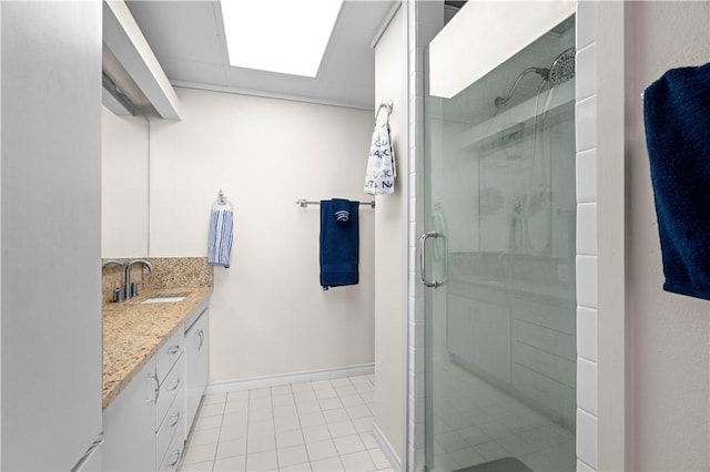 bathroom with a shower with door, vanity, tile patterned flooring, and a skylight