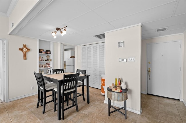 tiled dining room featuring ornamental molding and built in features