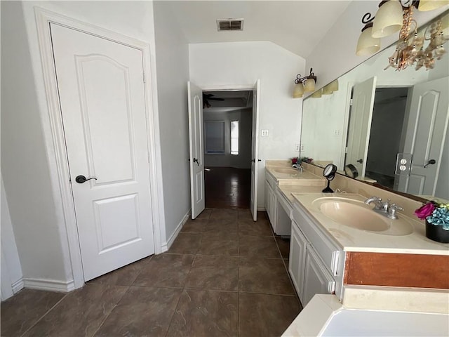 bathroom featuring tile patterned flooring, visible vents, double vanity, vaulted ceiling, and a sink