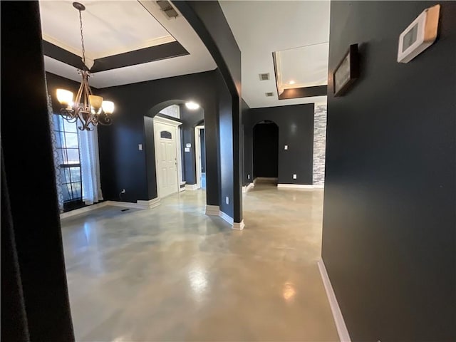 entrance foyer featuring baseboards, concrete flooring, a tray ceiling, arched walkways, and a notable chandelier