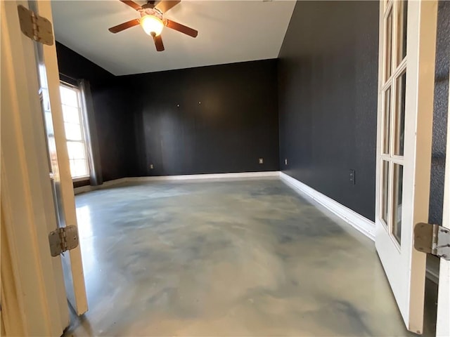 unfurnished room featuring ceiling fan, concrete flooring, and baseboards