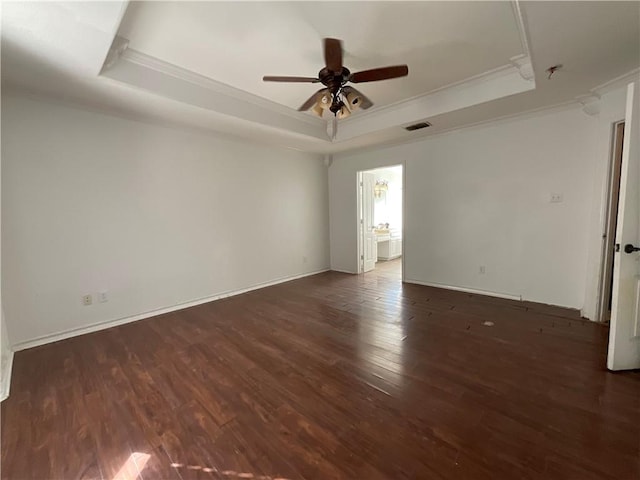 spare room with visible vents, a raised ceiling, wood finished floors, and ornamental molding