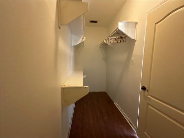 walk in closet with dark wood finished floors and visible vents