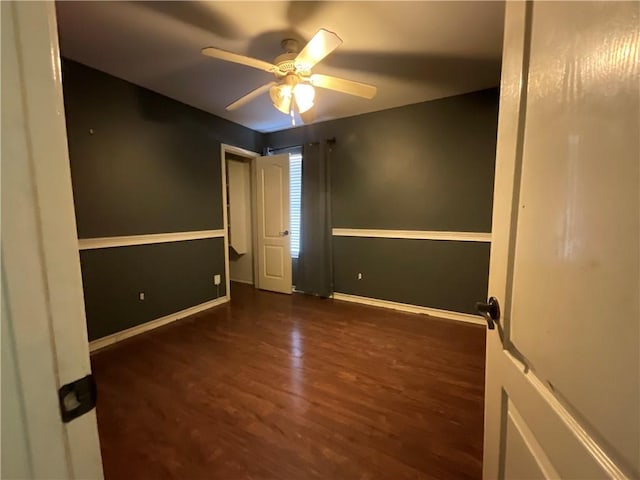 empty room featuring baseboards, a ceiling fan, and wood finished floors