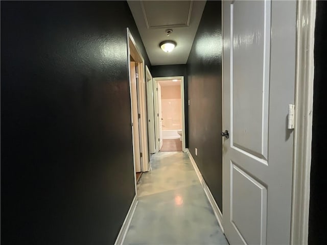 corridor with finished concrete flooring and baseboards