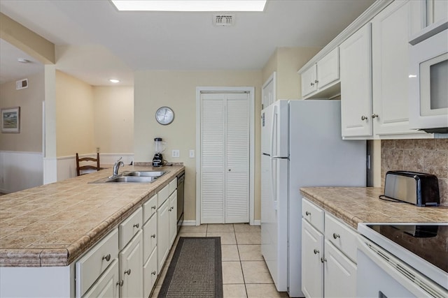 kitchen featuring tasteful backsplash, light tile patterned floors, sink, white cabinets, and white appliances