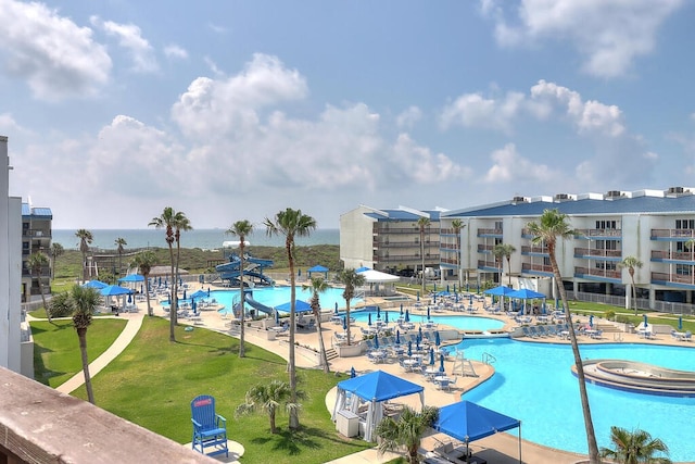 view of swimming pool featuring a patio, a yard, and a water view