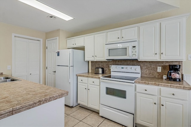 kitchen featuring tile countertops, white cabinets, light tile patterned floors, backsplash, and white appliances