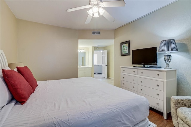 bedroom featuring light hardwood / wood-style floors, ceiling fan, and ensuite bathroom