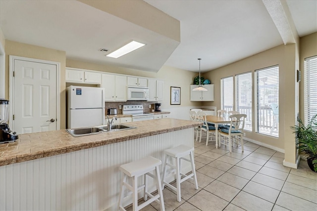 kitchen featuring white cabinetry, sink, tasteful backsplash, hanging light fixtures, and white appliances